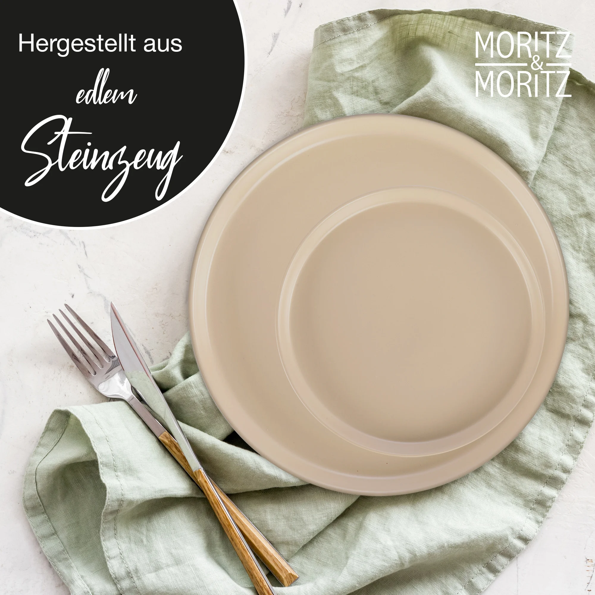 Zwei schwarze Edelstahl-Thermobecher der Marke Moritz & Moritz stehen nebeneinander auf einem Küchentisch; einer mit geschlossenem Deckel, der andere mit geöffnetem Deckel und sichtbarem Trinkaufsatz, im Hintergrund befinden sich verschwommen Küchenutensi