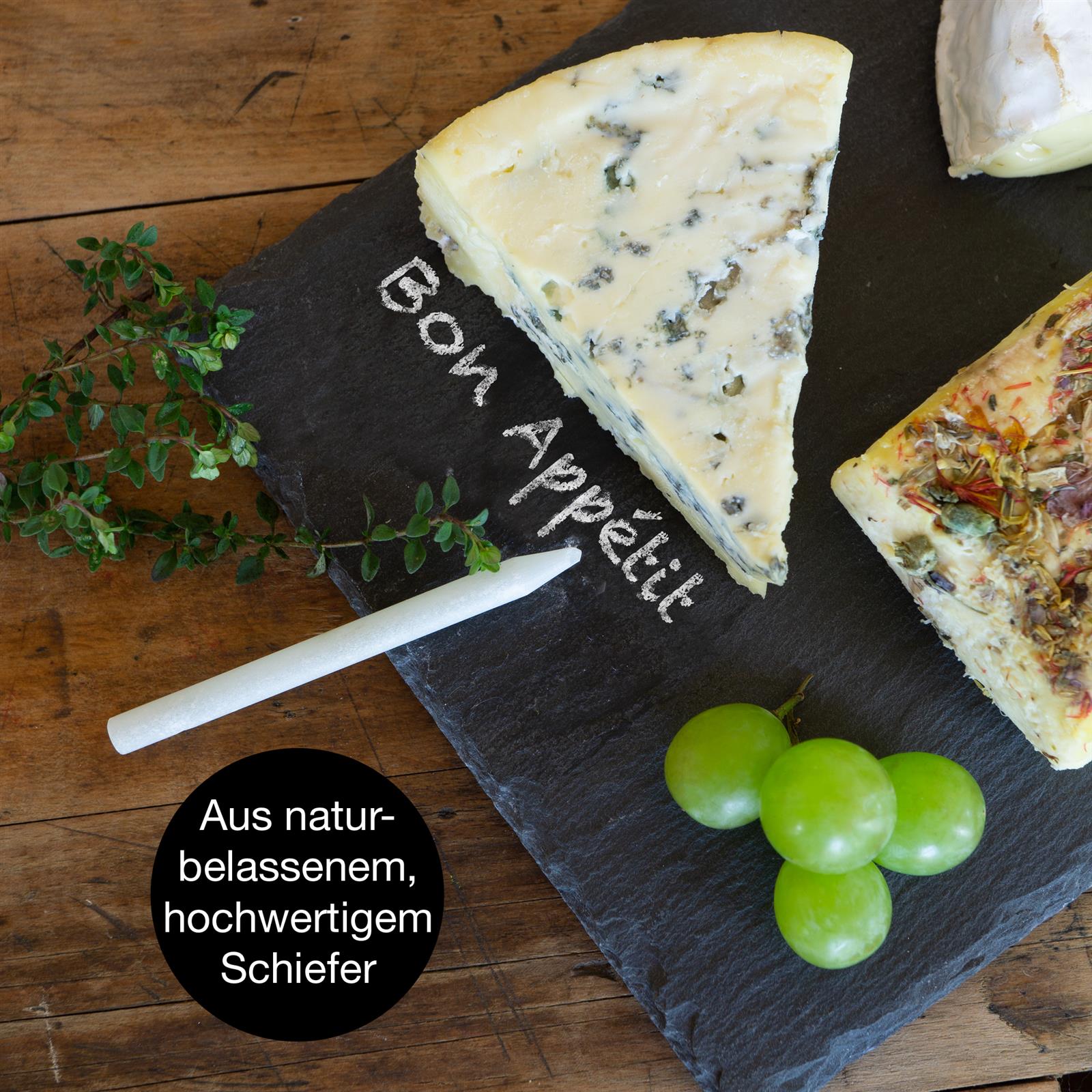 Schieferplatte mit dünn geschnittenem Schweinebraten, dekoriert mit frischem Thymian, Pfefferkörnern und Knoblauch
