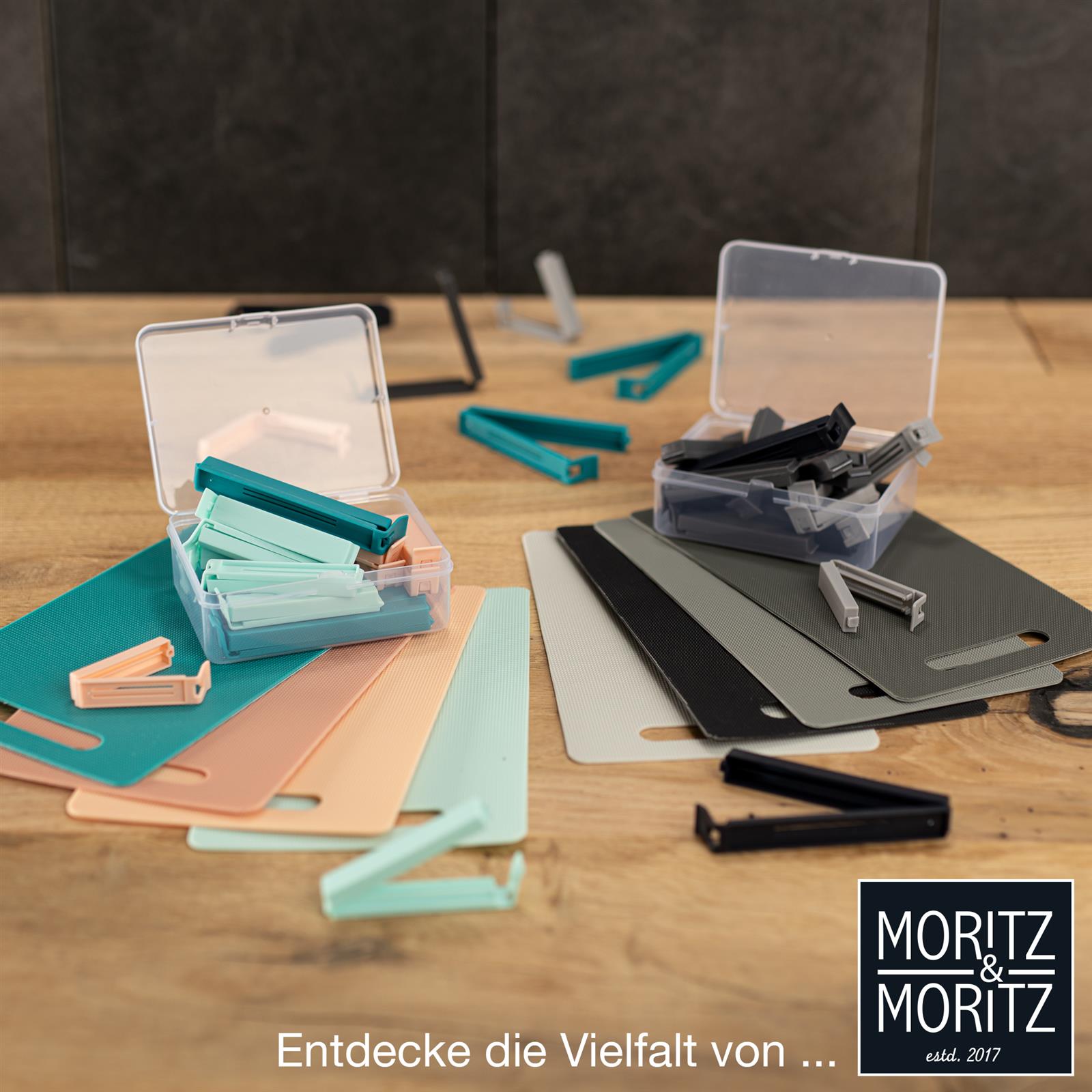 Mehrfarbige Kunststoff-Verschlussclips in Rot, Blau, Grün, Gelb und Violett liegen sortiert auf einer weißen Oberfläche