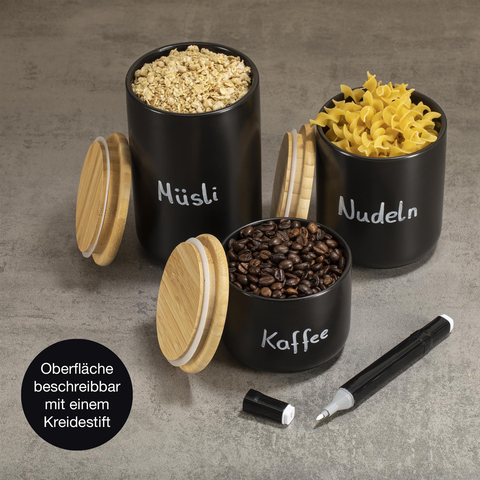 3er Set Keramik Aufbewahrungsbecher mit Deckel – Stilvolle Vorratsdosen in Naturfarben Drei Keramik-Aufbewahrungsbecher mit Holzdeckeln in Blau-, Beige- und Grautönen stehen nebeneinander auf einer hellen Arbeitsfläche; jeder Becher hat ein geometrisches Muster und dient zur Aufbewahrung von Lebensmitteln.