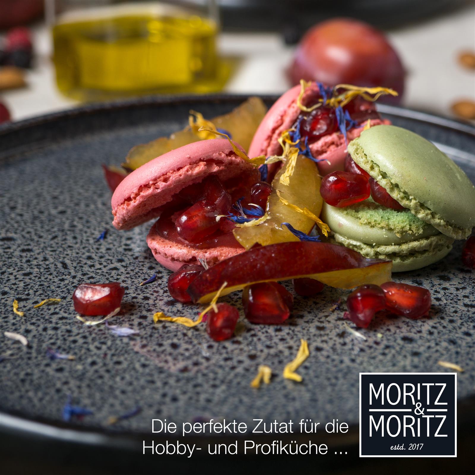 Grauer Gourmet-Dessertteller mit kunstvoll angerichtetem Dessert, verziert mit Früchten und essbaren Blüten