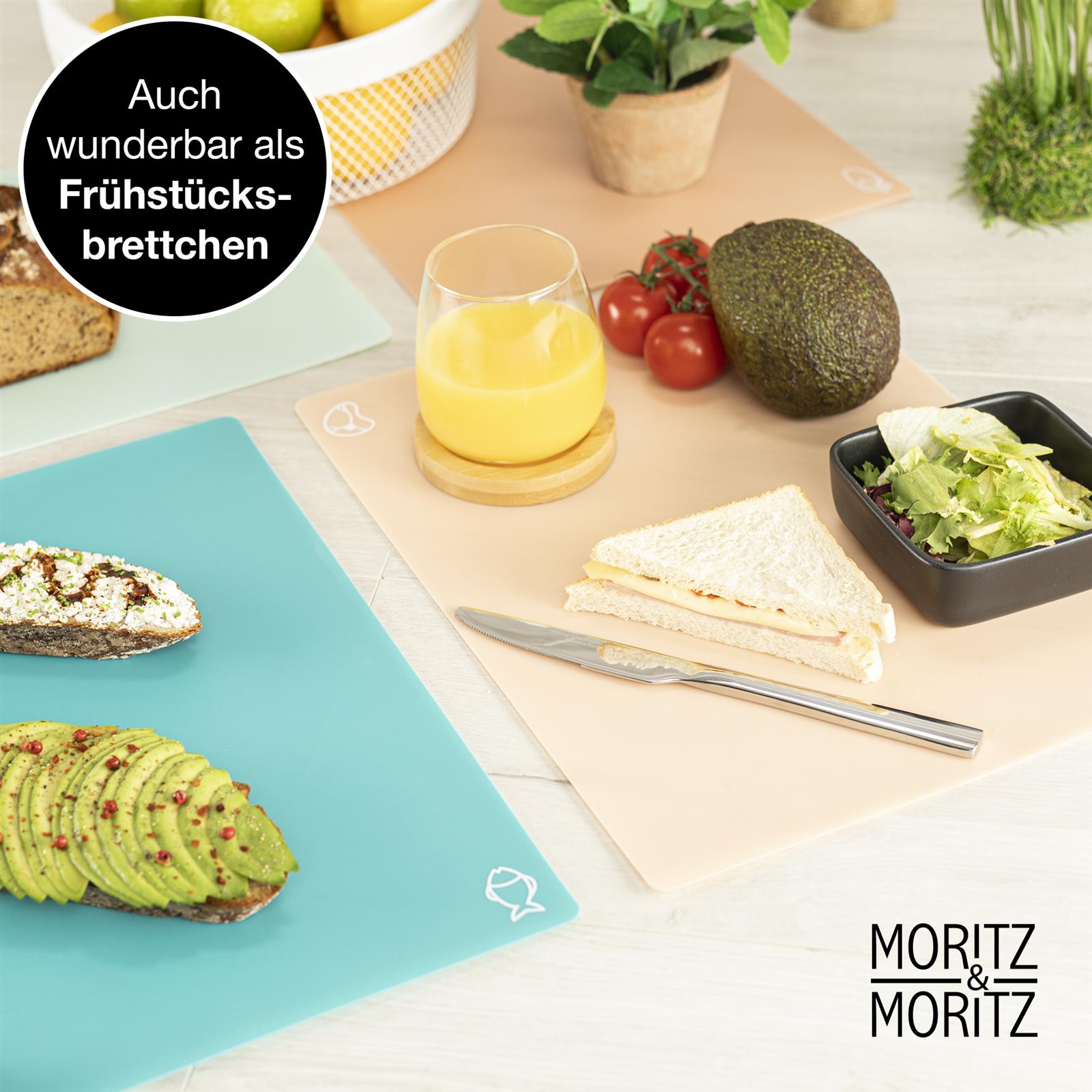 Vier farbige flexible Schneideunterlagen aus Kunststoff sind nebeneinander auf einer hellen Küchenarbeitsplatte angeordnet