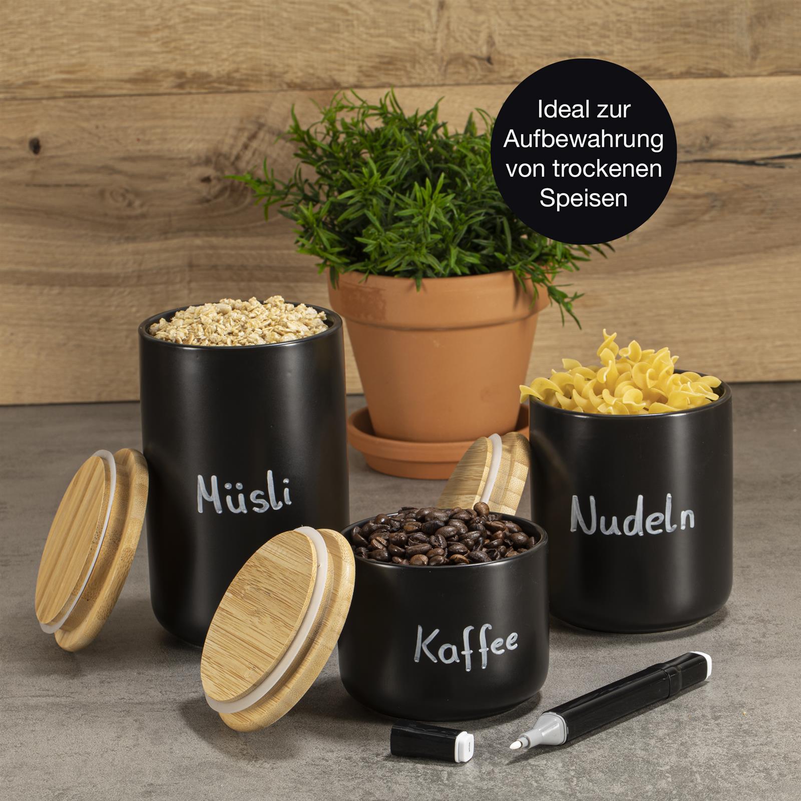 3-teiliges Keramik Aufbewahrungsbecher Set in Beige mit Deckel – stilvolle Vorratsdosen für Küche und Haushalt Drei zylindrische Keramik-Aufbewahrungsbecher mit Holzdeckeln in einer Reihe auf einem Holztisch; die Becher sind in matten Farbtönen gehalten – Hellgrau, Dunkelgrau und Beige – und jeweils mit einem Holzlöffel versehen, im Hintergrund unscharfe Küchenute