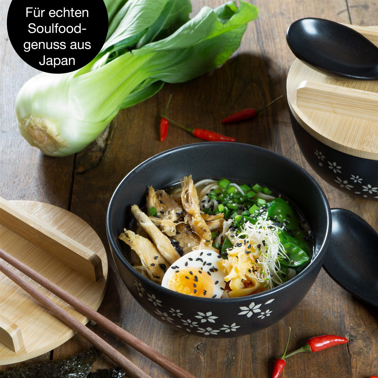 Zwei Gourmet-Ramen-Schalen mit dekorativen Blumenmustern auf den Deckeln, präsentiert auf einer, dunklen Oberfläche