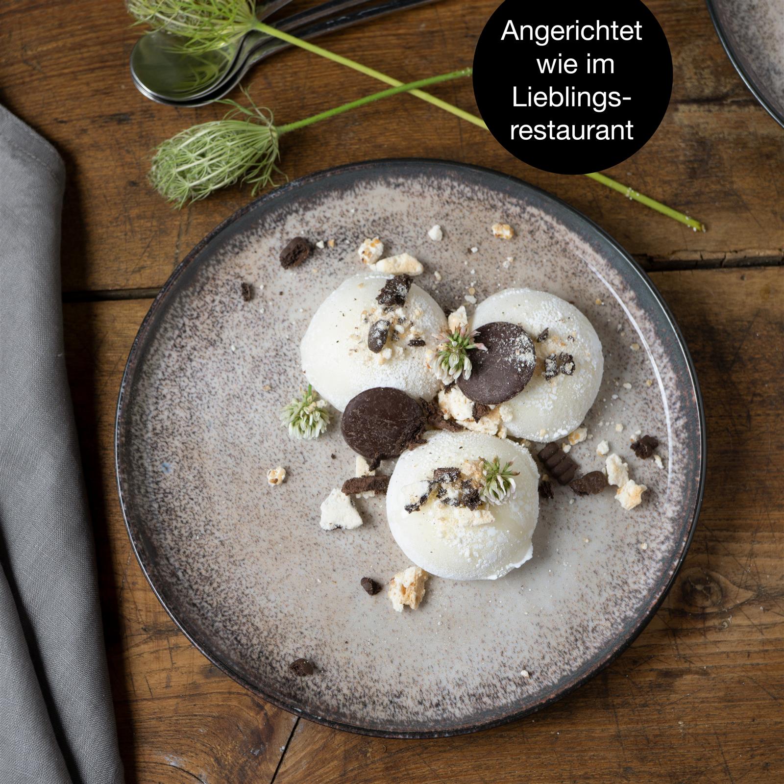 Tellerset in Beige, Sechsteiliges beigefarbenes Salatteller-Set aus Keramik, auf Holztisch angerichtet mit frischem Salat