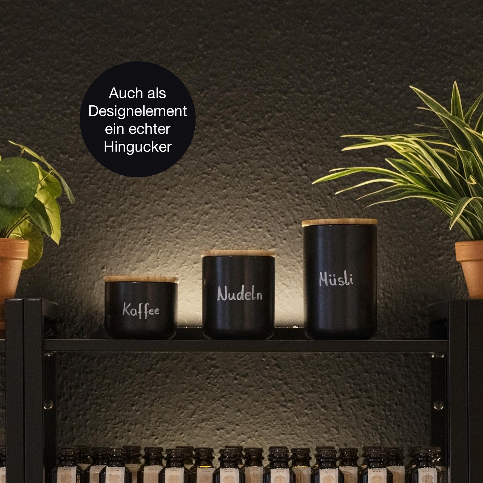 3-teiliges Keramik Aufbewahrungsbecher Set mit Holzdeckel – Vorratsdosen in Weiß für Küche und Haushalt Dreiteiliges Set aus zylindrischen Keramik-Aufbewahrungsbechern mit Holzdeckeln in verschiedenen Farben – Cremeweiß, Dunkelgrau und Zartrosa – auf einer Küchenarbeitsplatte arrangiert.