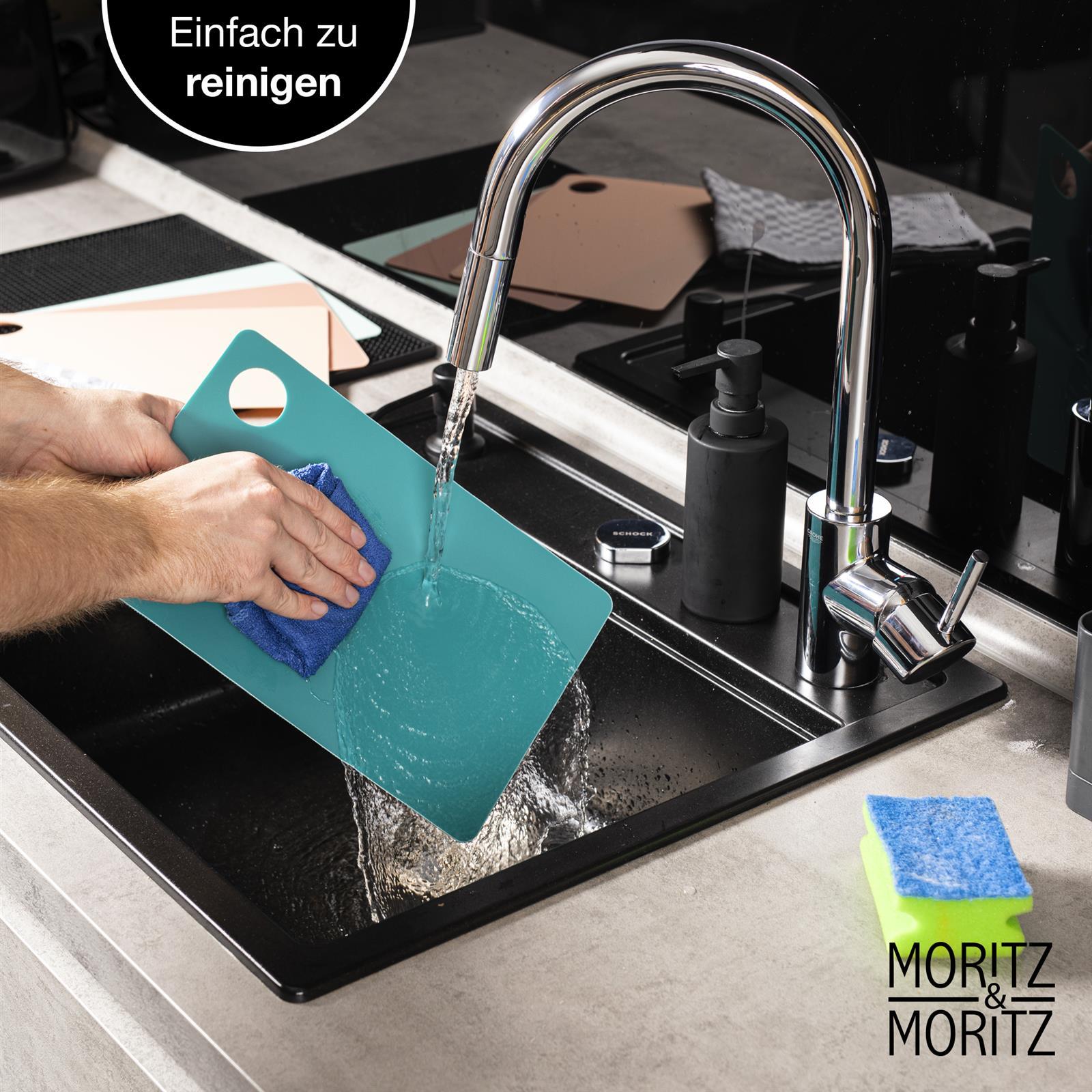 Bunte Schneideunterlage mit Markierungen für präzises Arbeiten Bunte Schneideunterlage aus Kunststoff für präzises Schneiden und Schutz der Arbeitsfläche, dekorativ auf einem Holztisch in einer modernen Küche platziert.