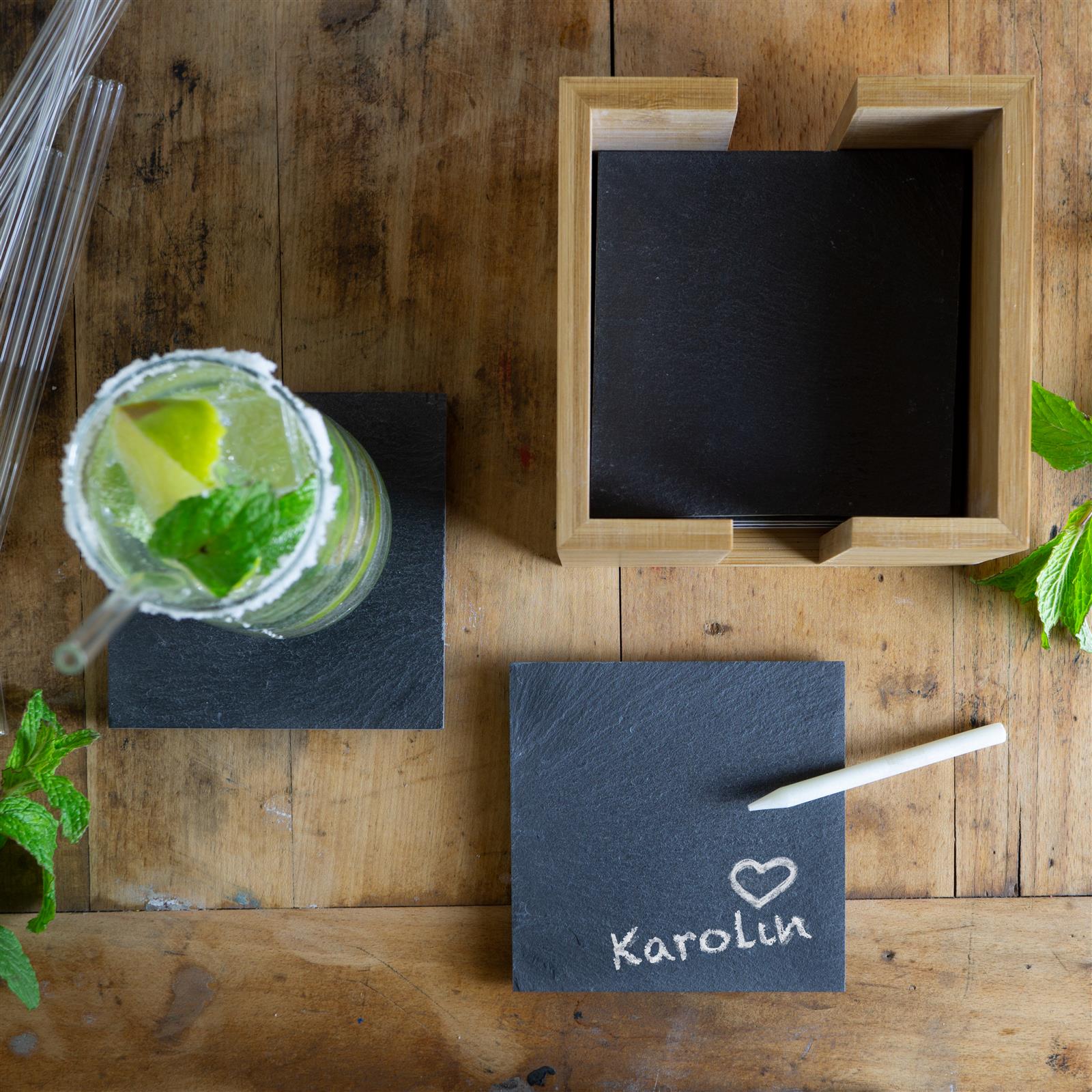 Moderne Schieferplatte mit Peppermint-Dip und Fingerfood – stilvoll serviert Zwei elegante Gläser mit schwarzem Schiefer-Cocktail auf Eiswürfeln, garniert mit frischer Minze, Limettenscheiben und einer Zimtstange, serviert auf einem dunklen Untergrund mit Kräutern und Limetten – erfrischender Pfefferminz-Drink in stilvollem Ambien